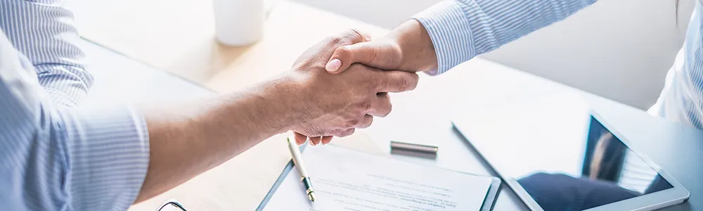 Handschlag zweier Arme über einem Vertrag